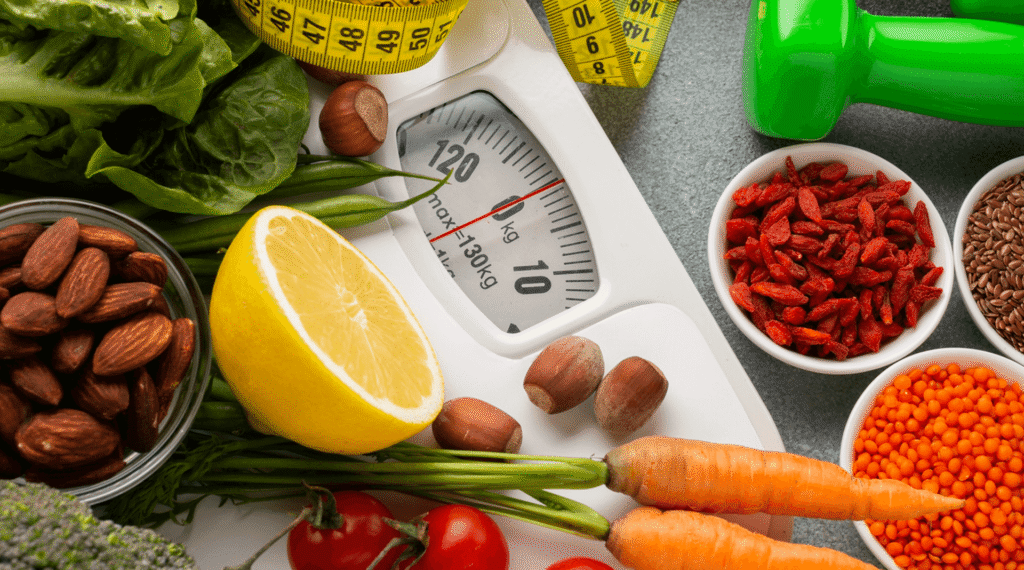 Bathroom scale surrounded by vegetables, nuts, lentils and a measuring tape