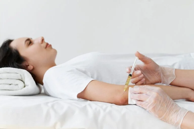 Patient lying on a treatment bed receiving an injection near the elbow
